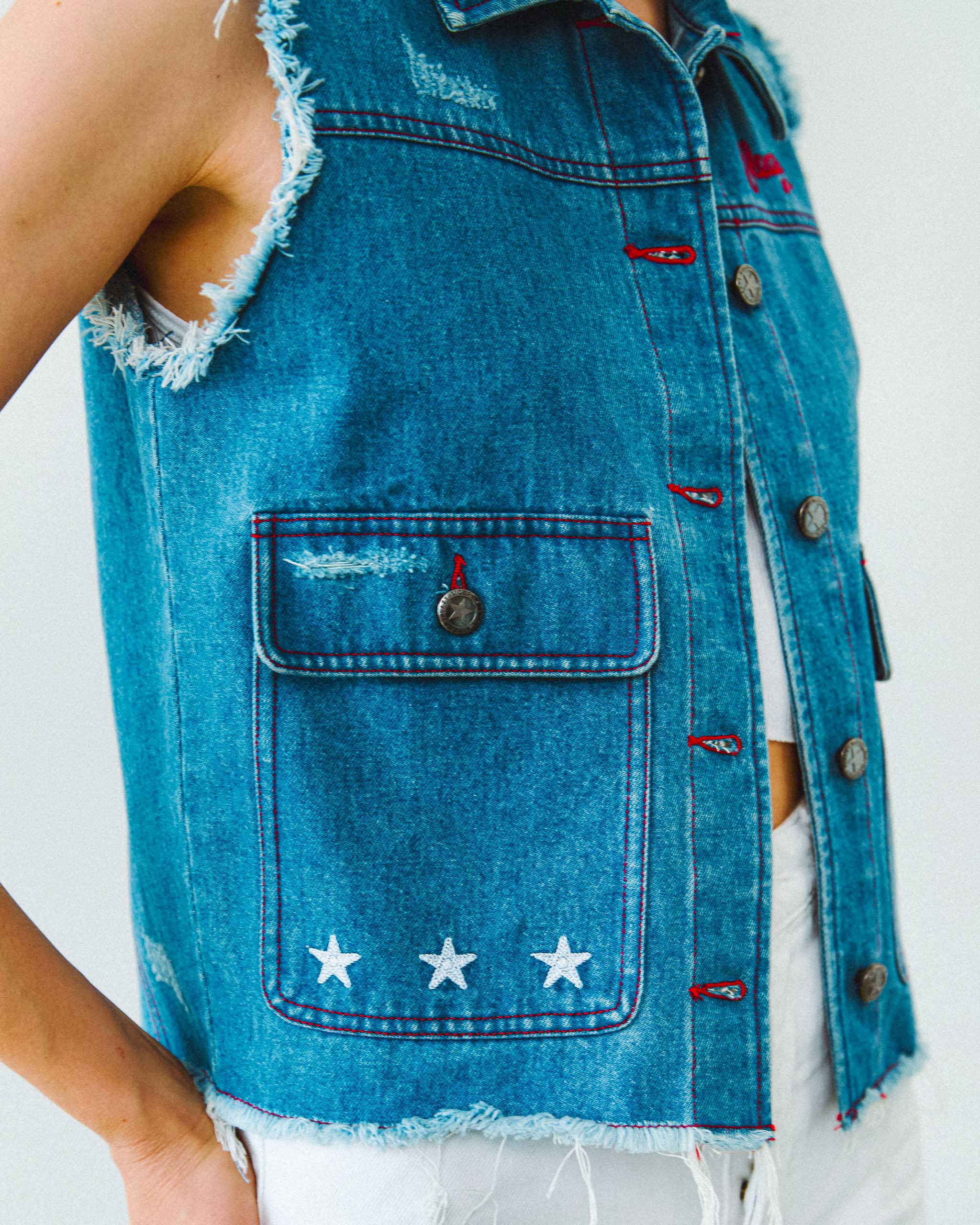 A denim vest with red contrast stitching, vintage distressed details and white chainstitch embroidery stars.