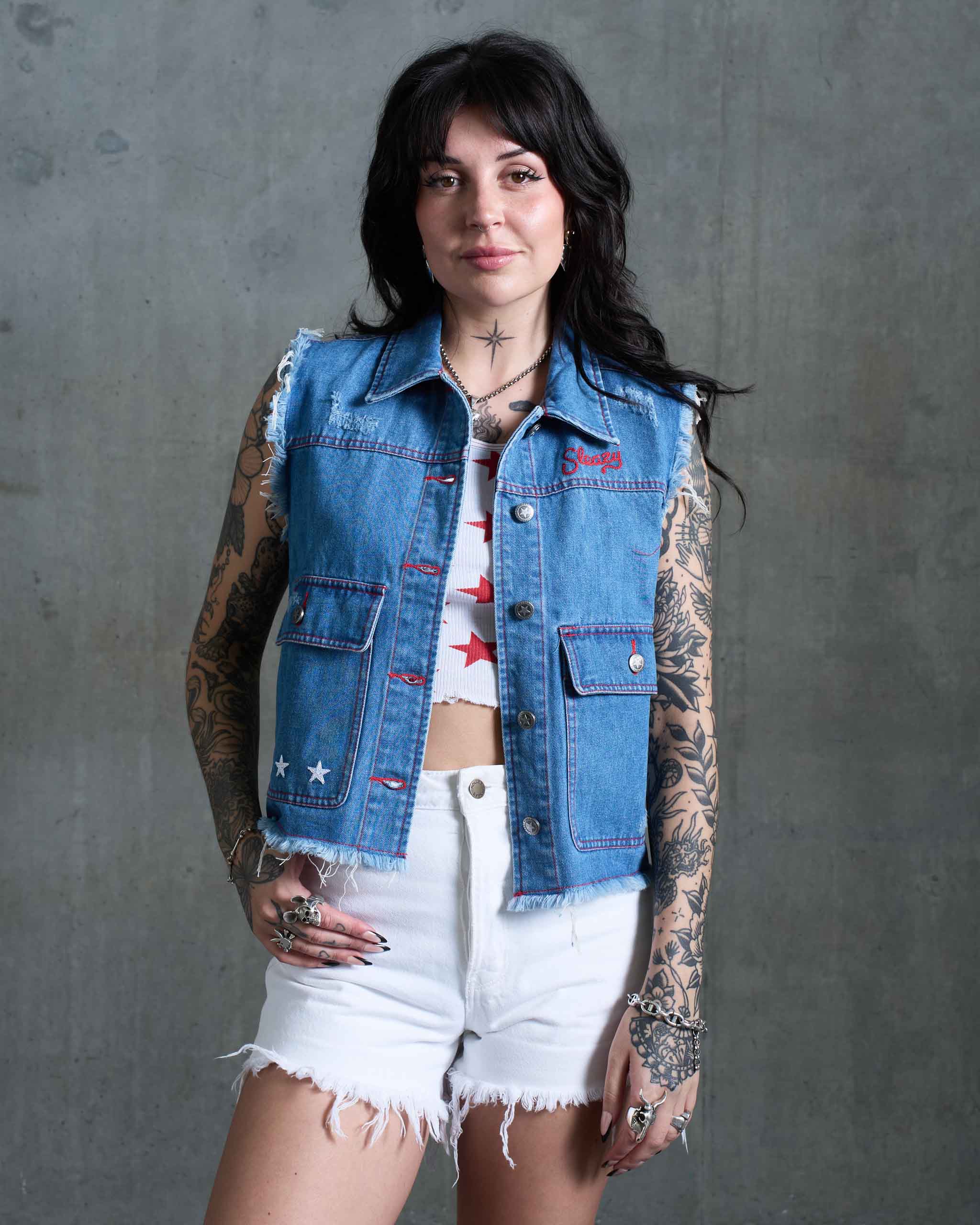 An Americana woman wearing a denim vest with red stitching and stat embroidery.