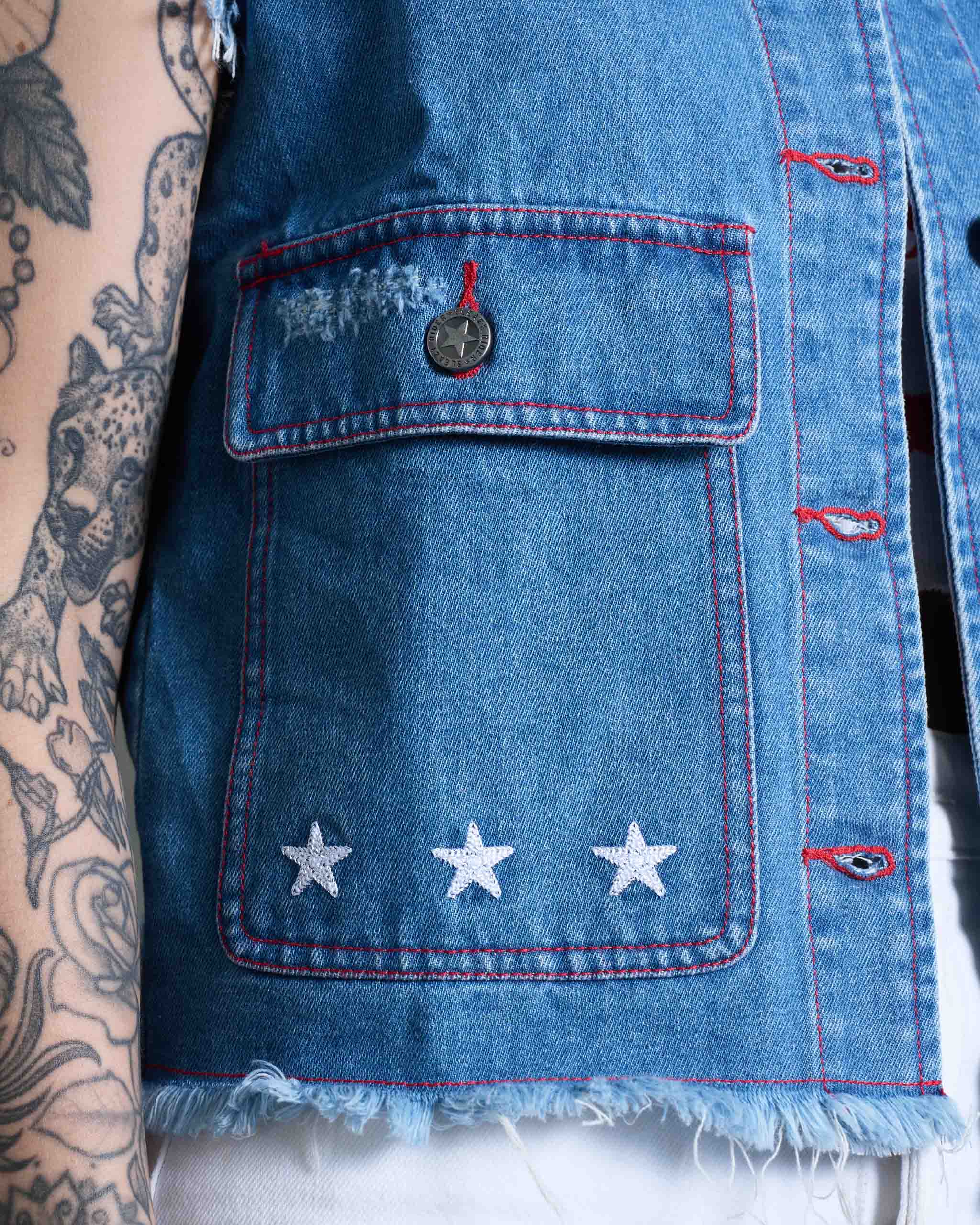 A denim vest with red stitching and star chainstitch embroidery.