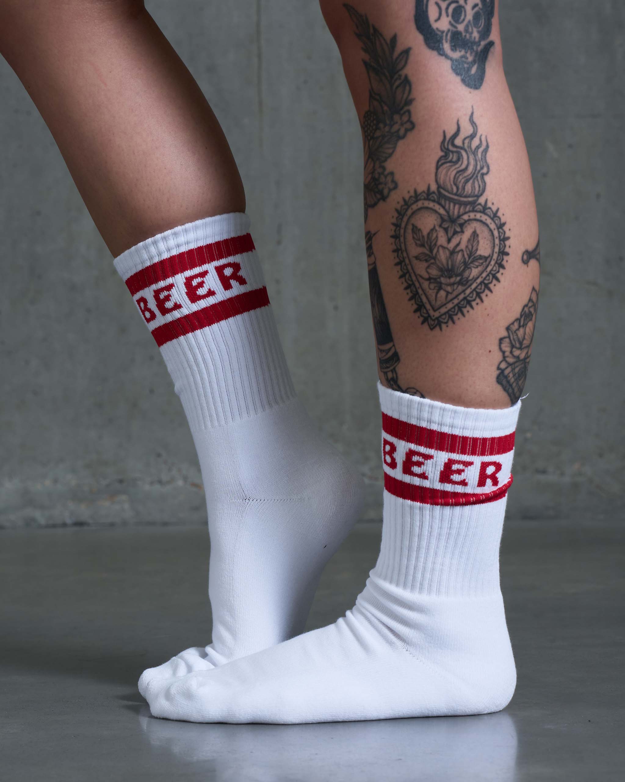 A tatooed woman wearing 'Beer' socks.