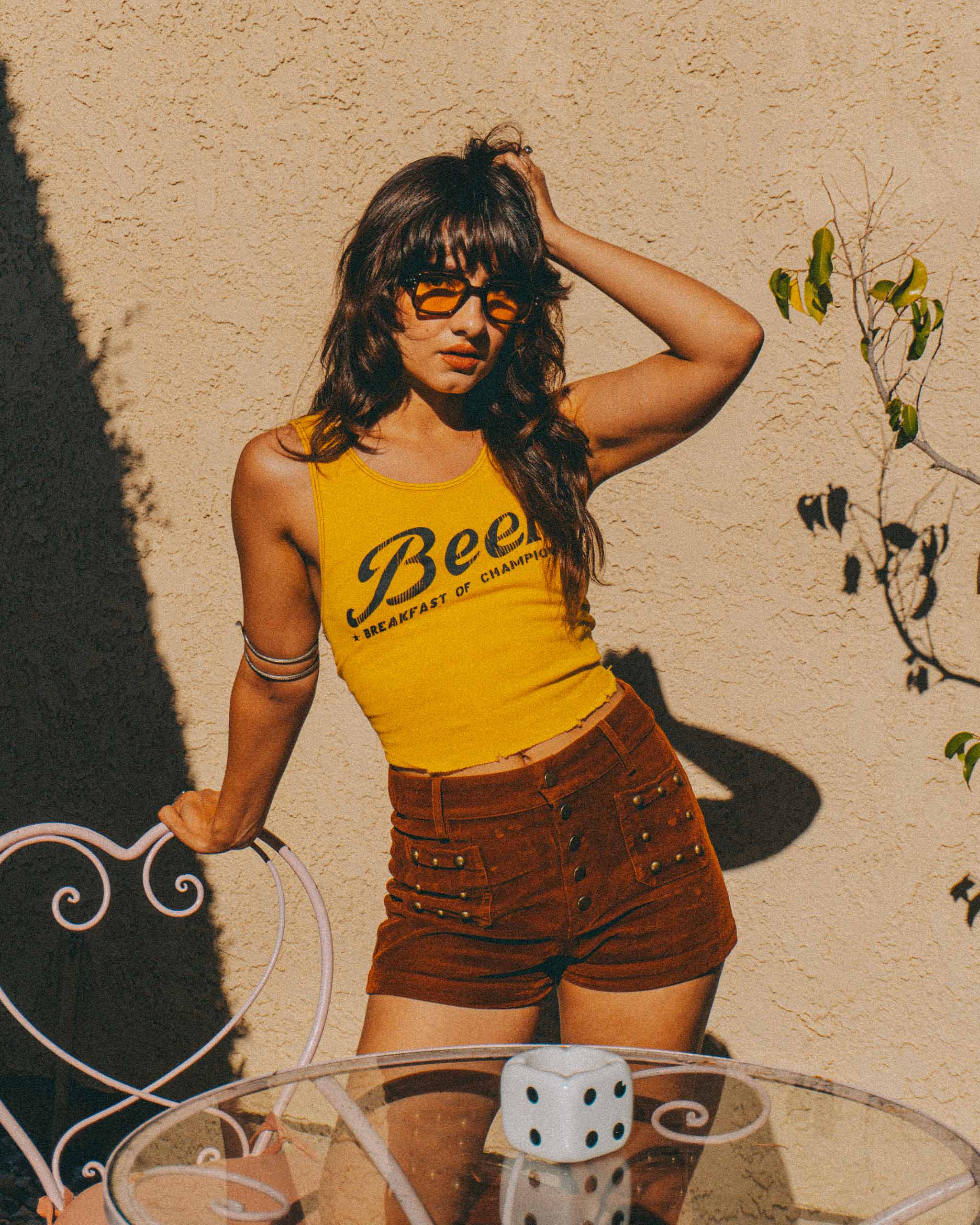 A 70's vintage style woman wearing a yellow tank top with 'Beer' text and 70s sunglasses.