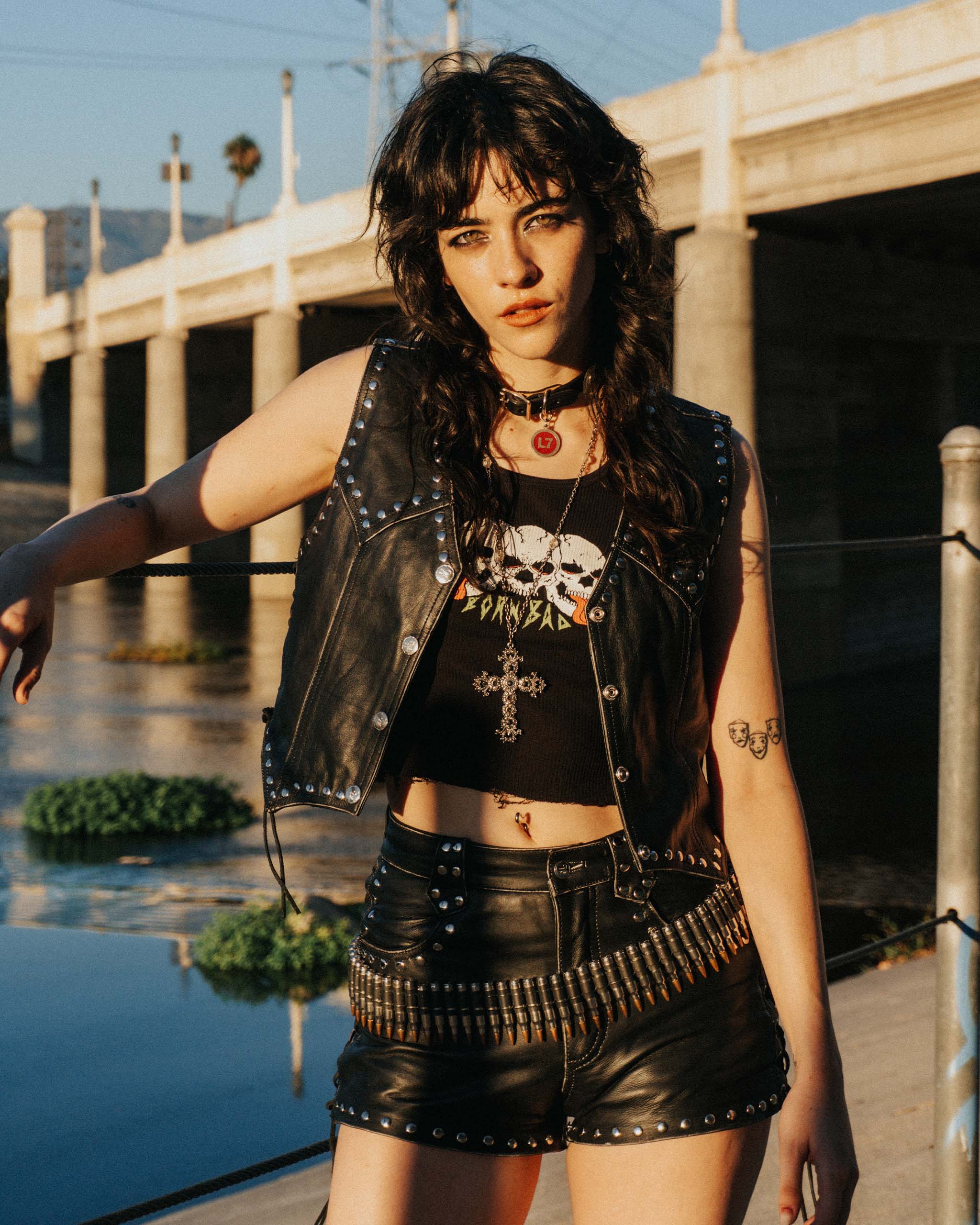 An alt gothic model in the Sleazy Rider Coyote Studded Leather vest and shorts with studded details standing by a river in California.