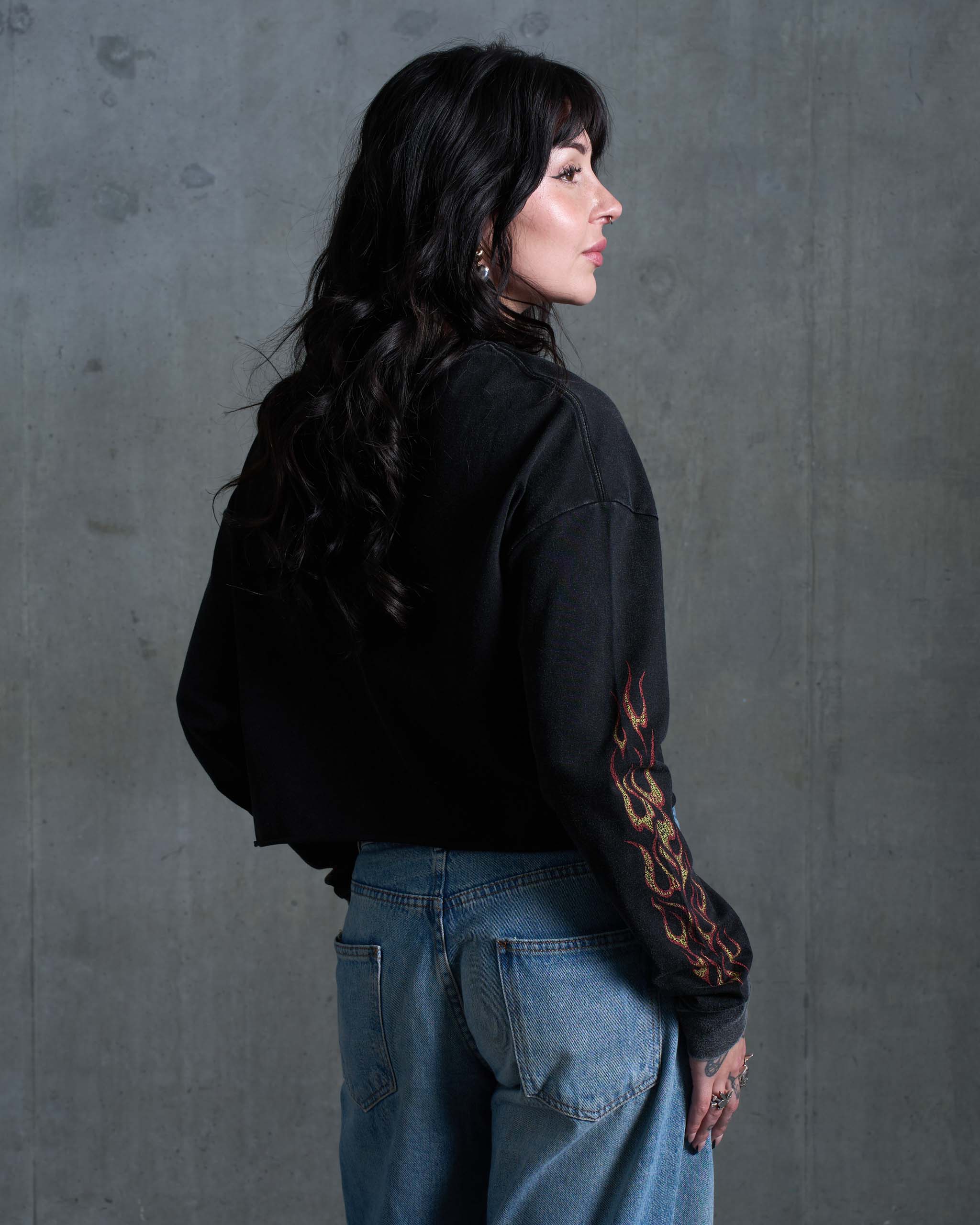 The back view of a woman wearing a long sleeve t-shirt with flames on the sleeves.