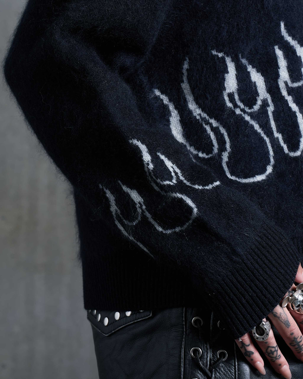 The sleeves of a gothic knitted sweater with flames on the sleeves.