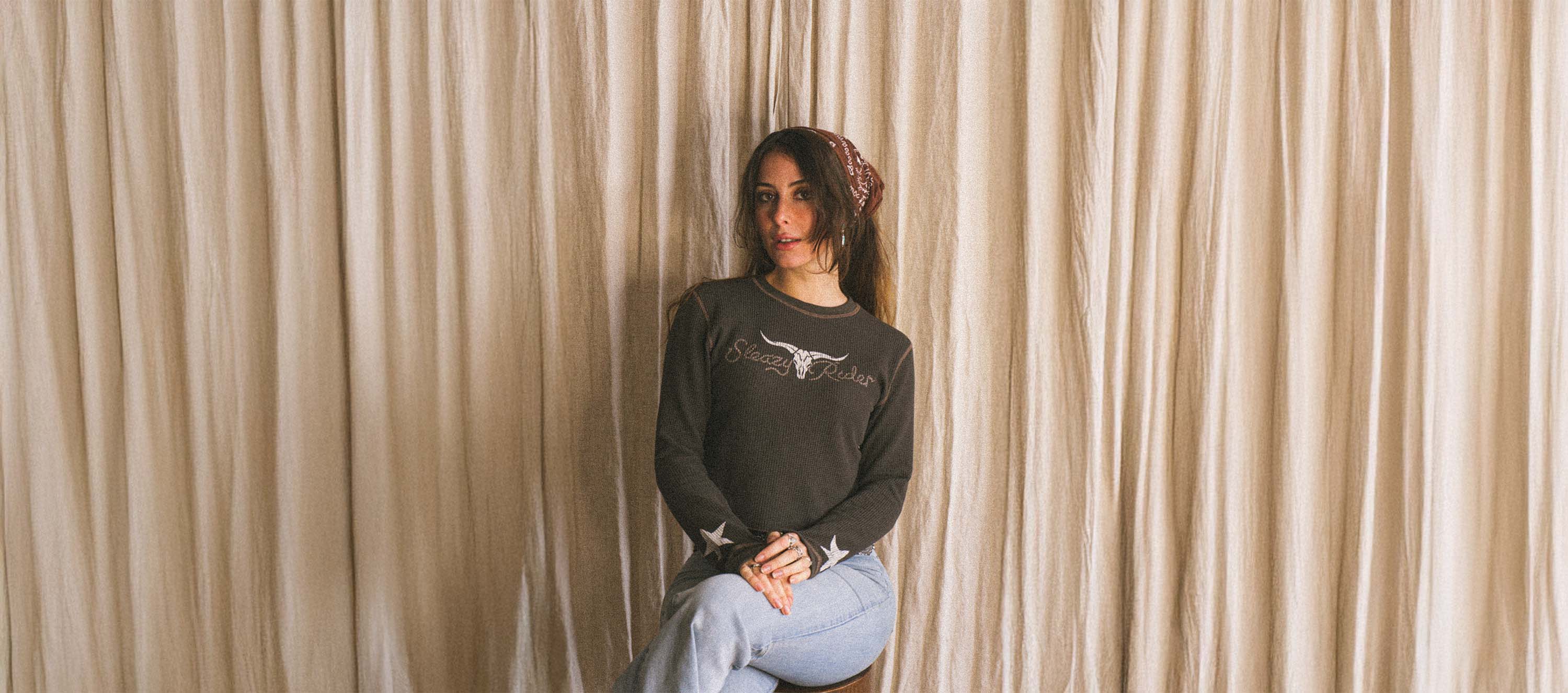 A woman wearing a waffle knit top with a texas longhorn skull print and stars on the sleeves.