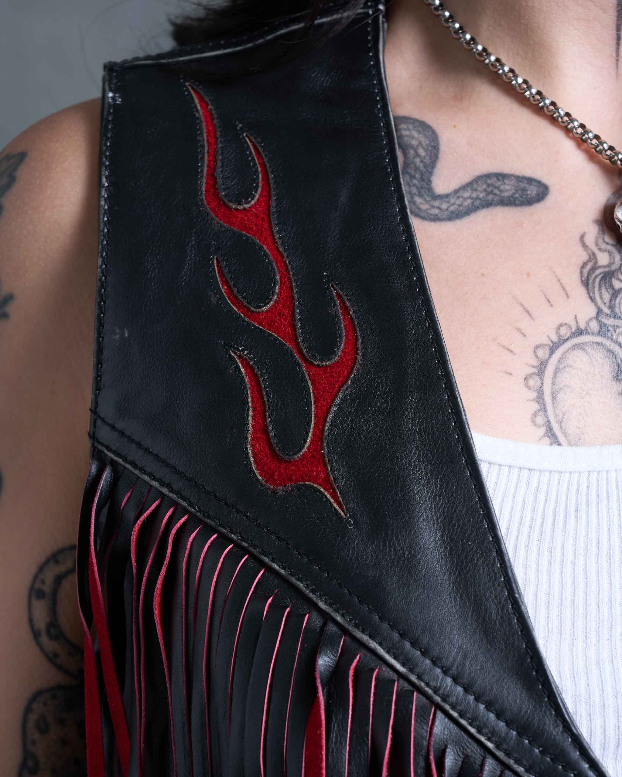 A close up of a women's biker leather vest with red flame suede detail,