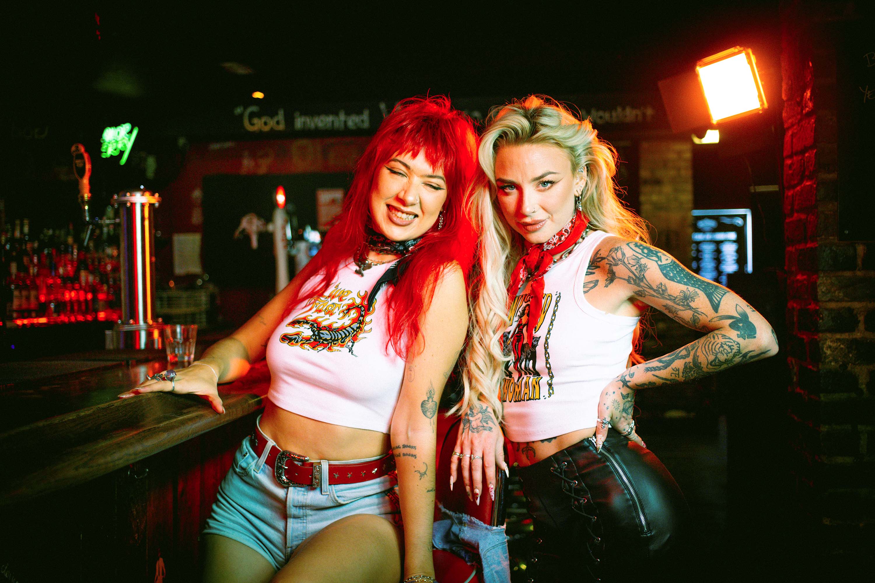 Amy Valentine and Rhianon Brailsford wearing Sleazy Rider in a dive bar
