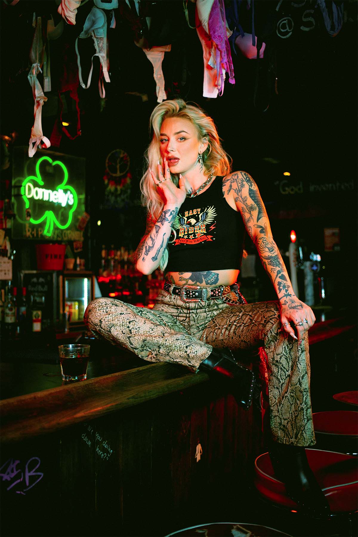 Rhianon Brailsford wearing a Sleazy Rider tank top in a dive bar
