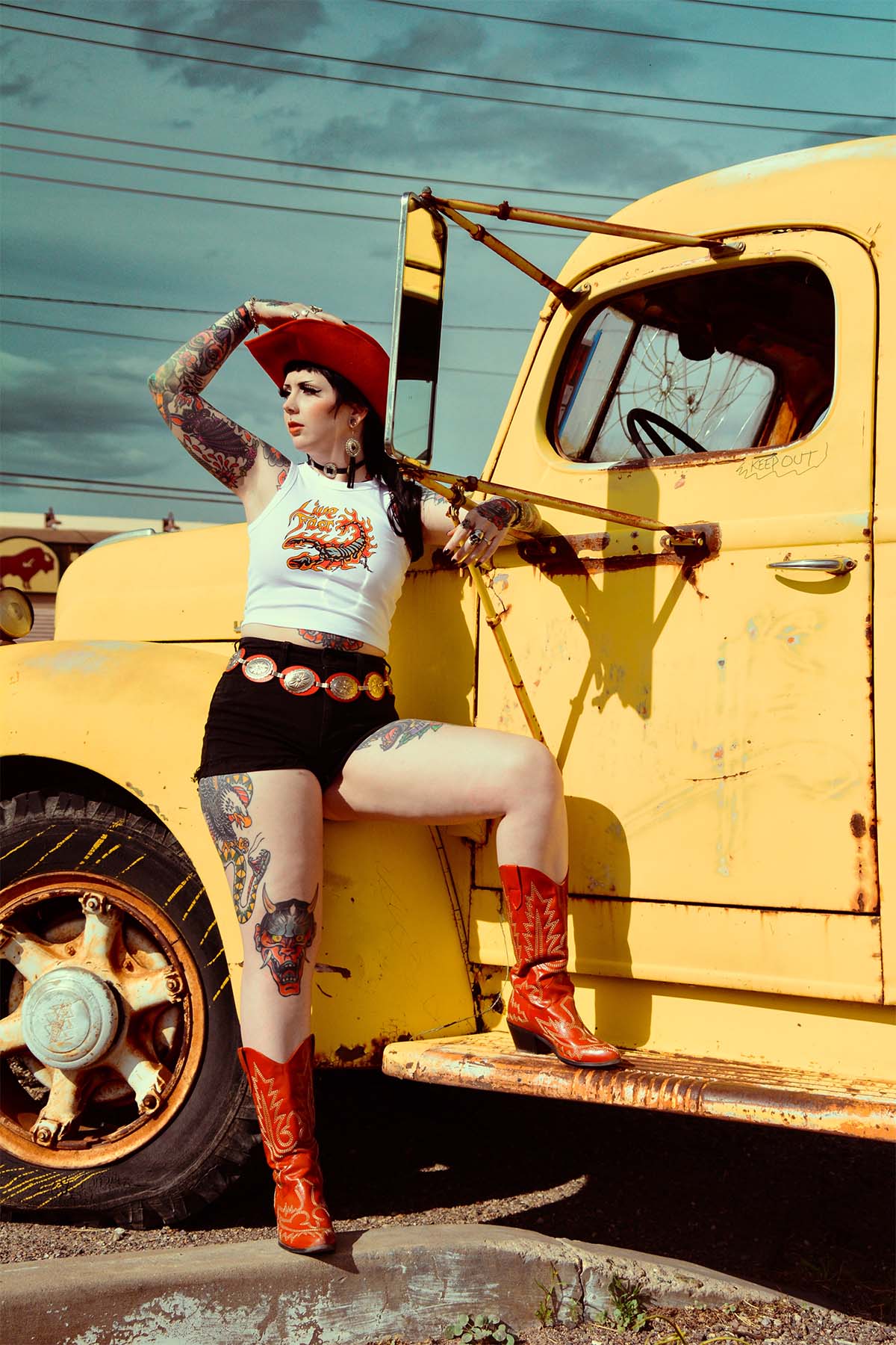 An alternative model wearing a Sleazy Rider tank next to a vintage American truck