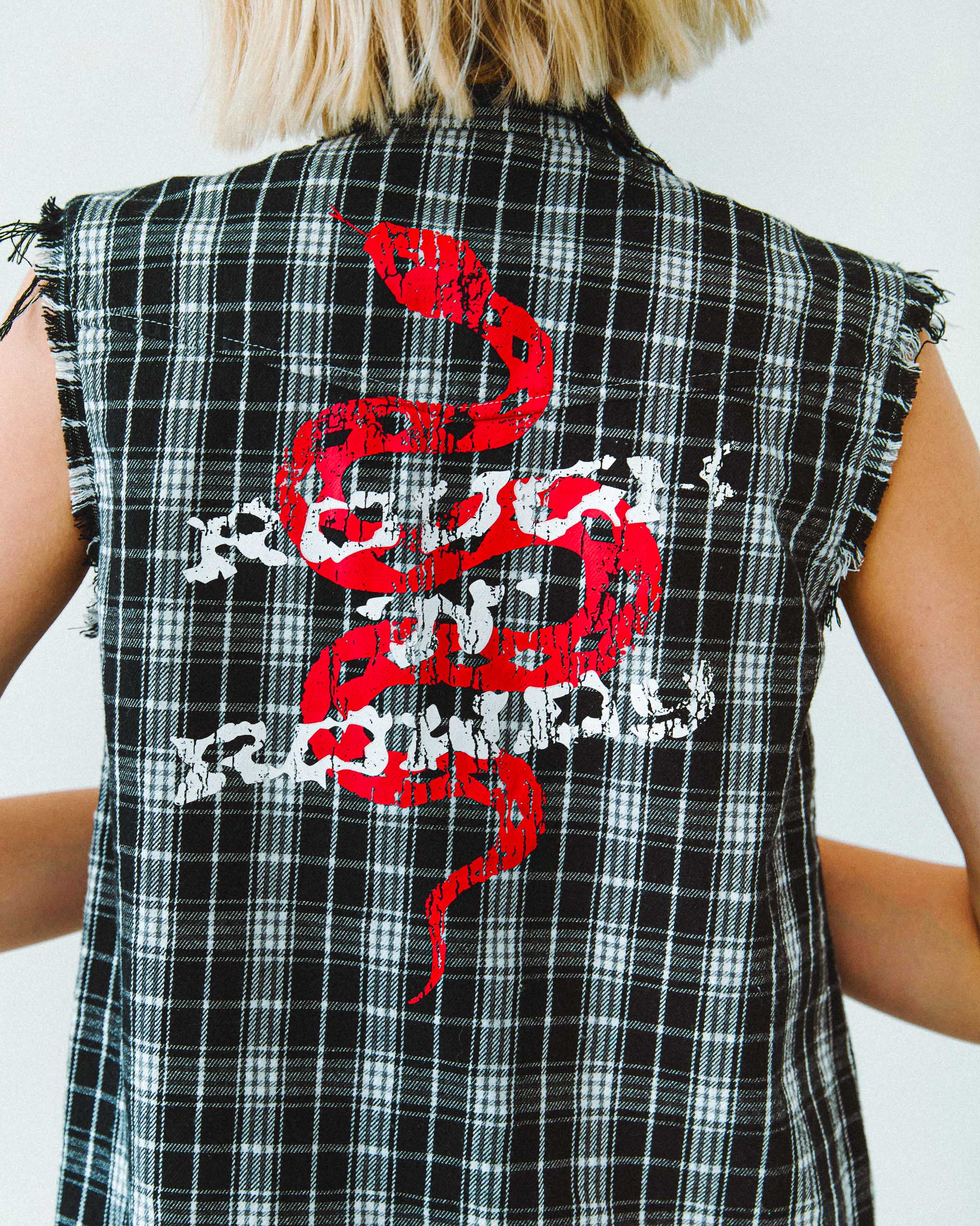 A black and white flannel cut off shirt, with a snake print on the back.