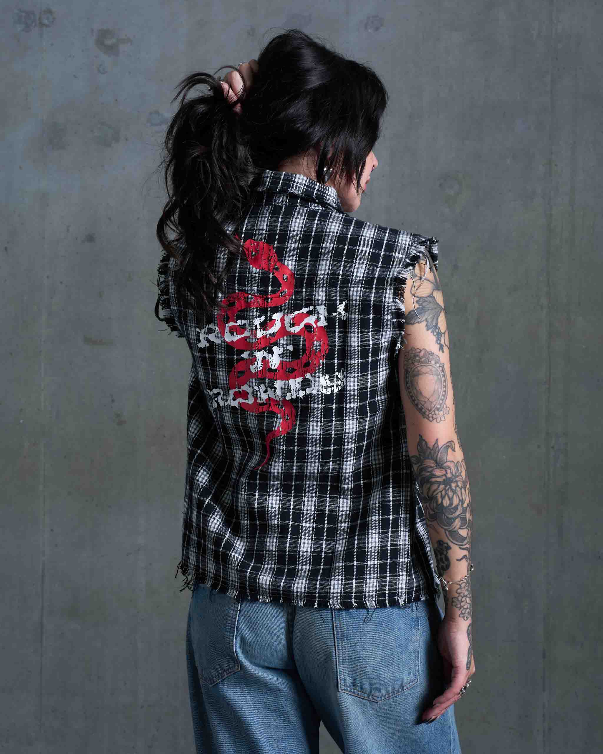 A woman wearing a flannel cut off and jeans.