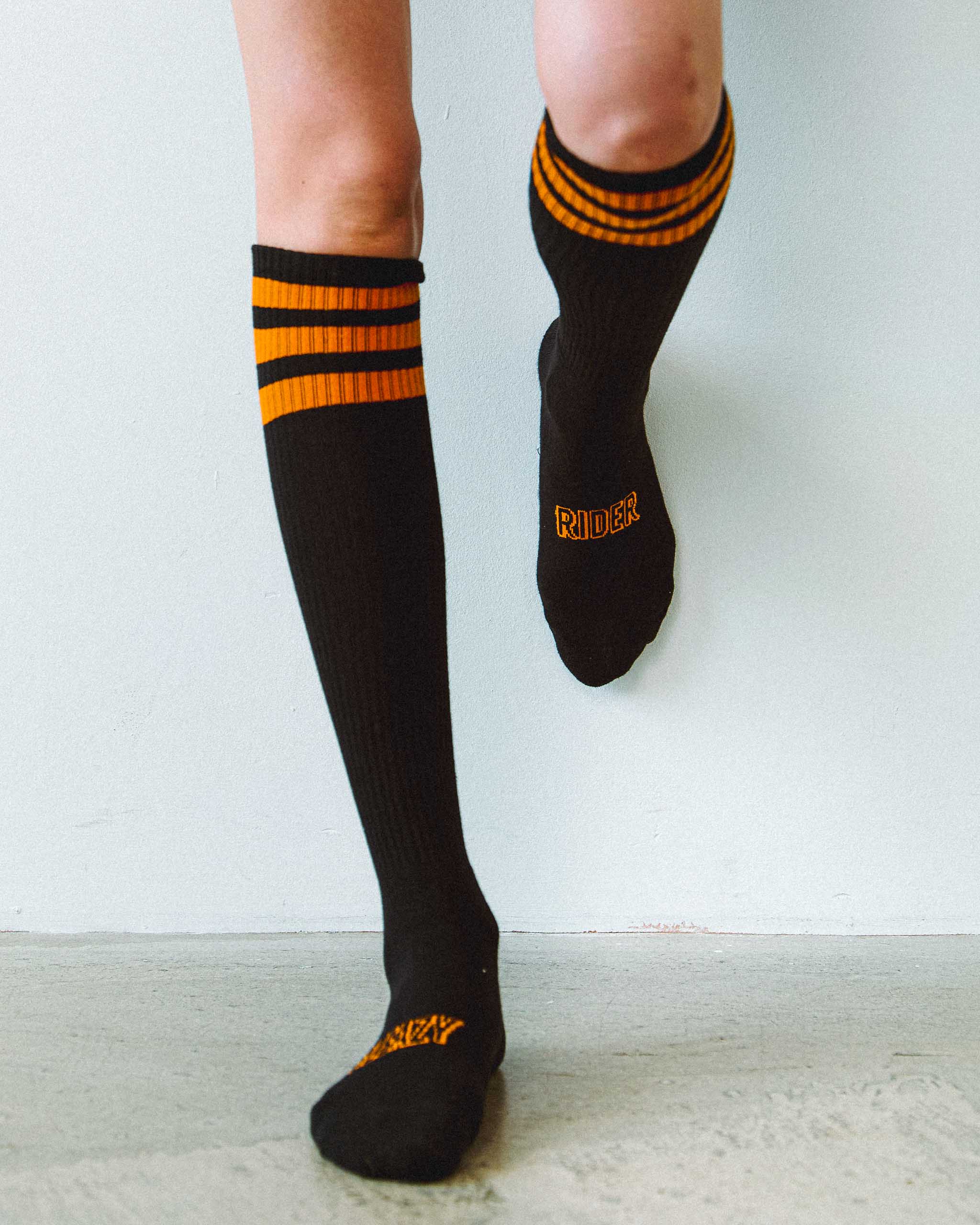Black knee-high socks with orange stripes and Sleazy Rider on them.