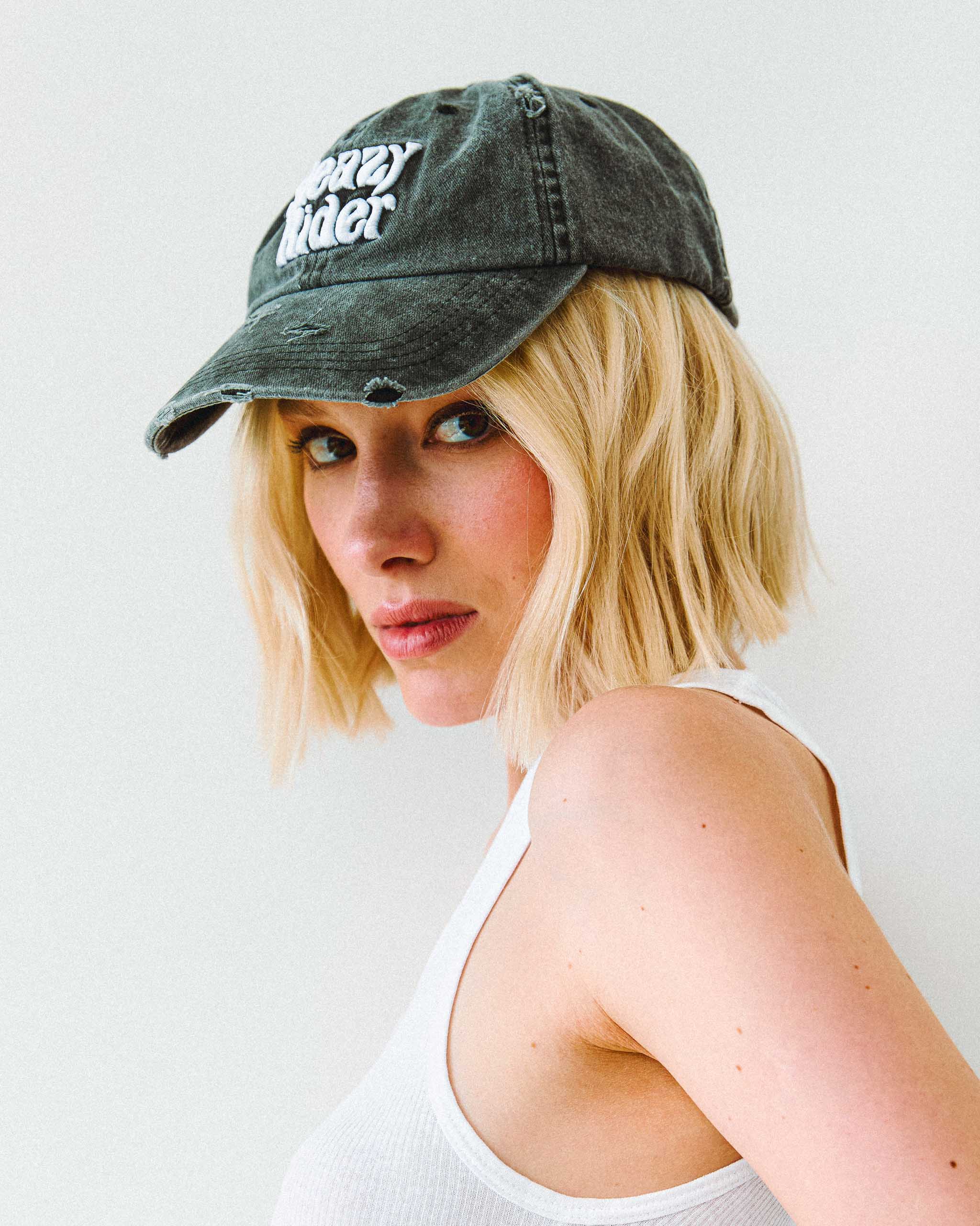 An alt model wearing a distressed Sleazy Rider cap.