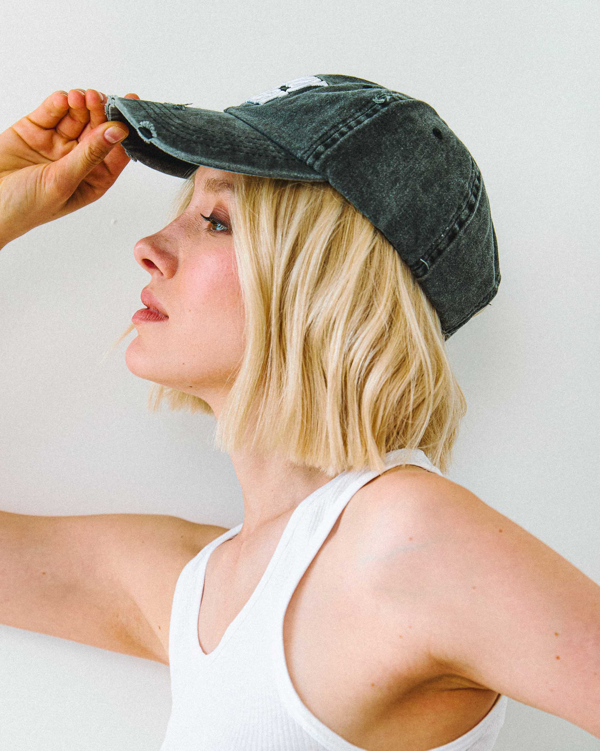 Woman wearing an acid wash vintage baseball cap against a plain background
