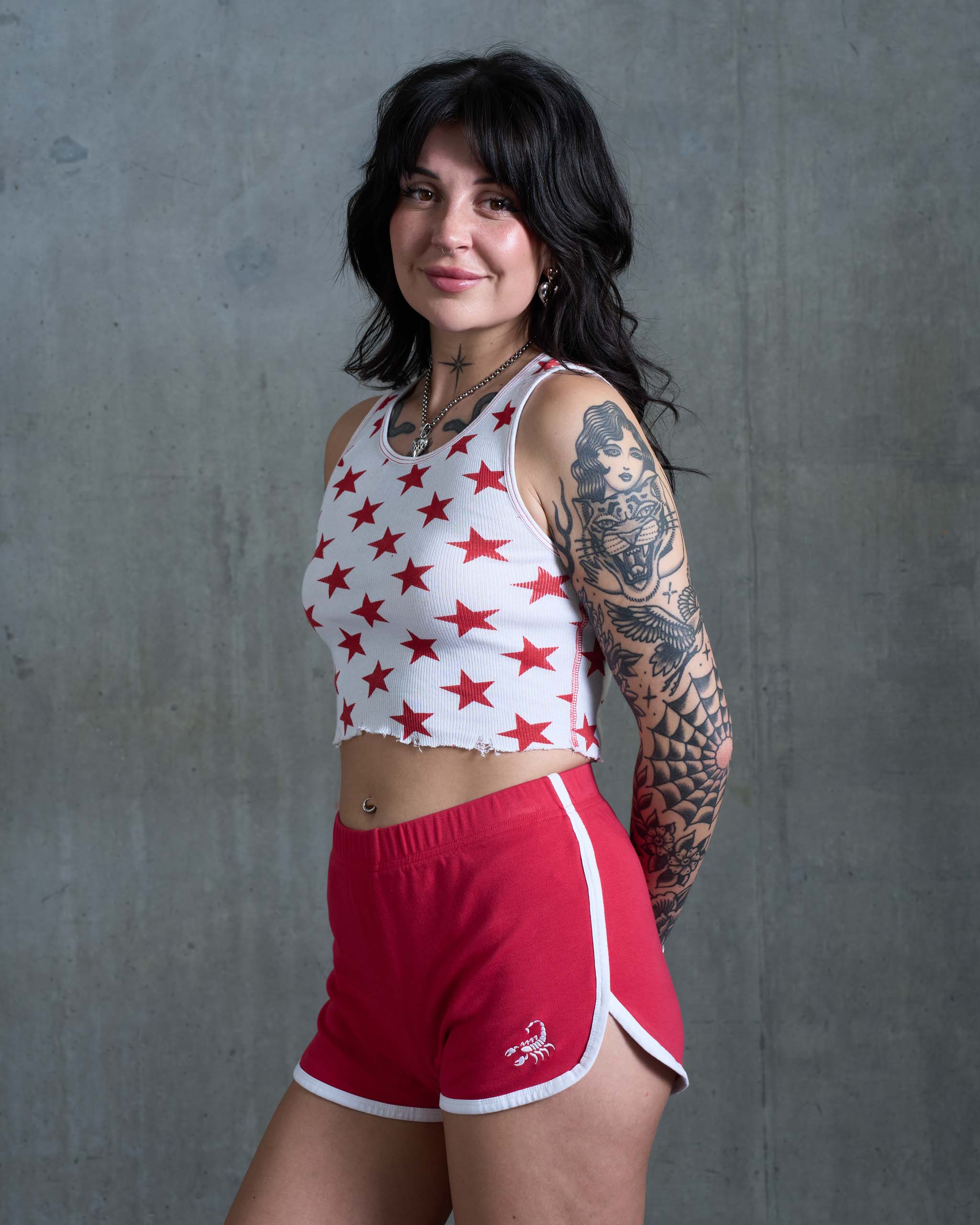 A tattooed woman wearing some vintage 80's sports shorts.