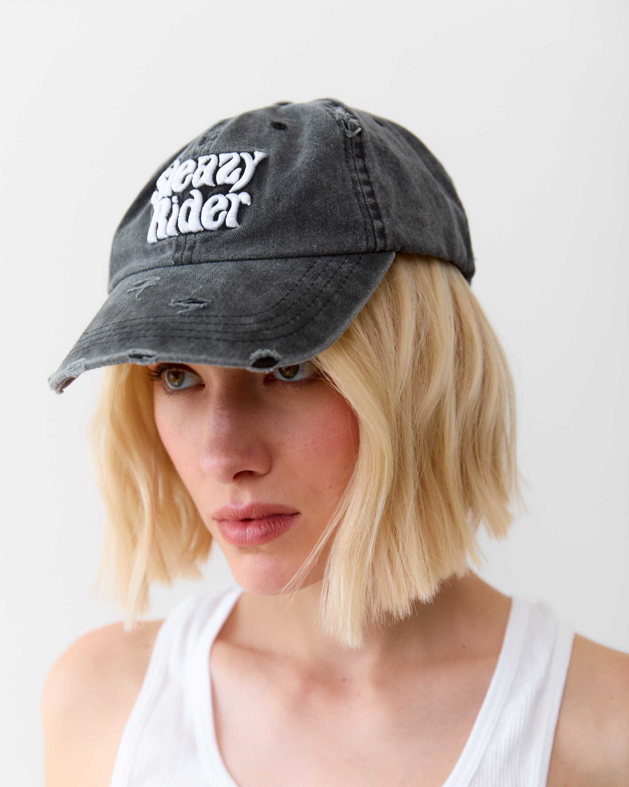 A woman wearing a Sleazy Rider distressed cap.