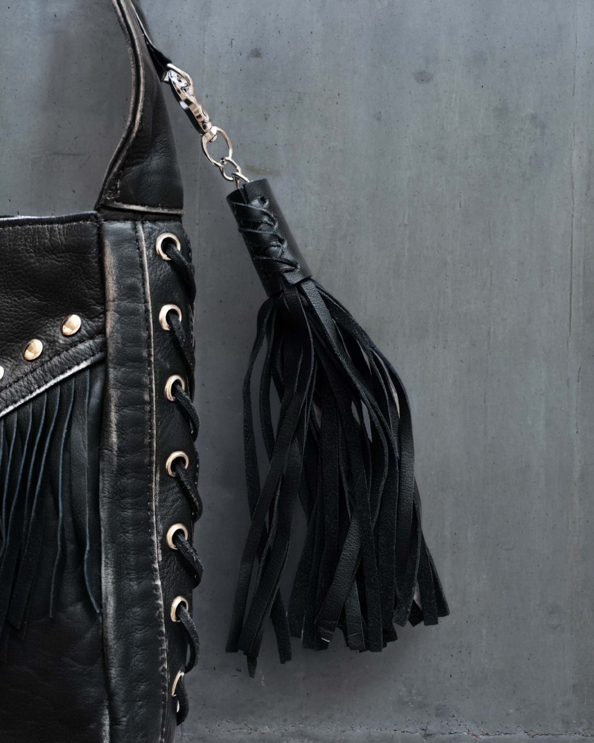 A leather bag charm, in the shape of a biker throttle cover with many western tassels.