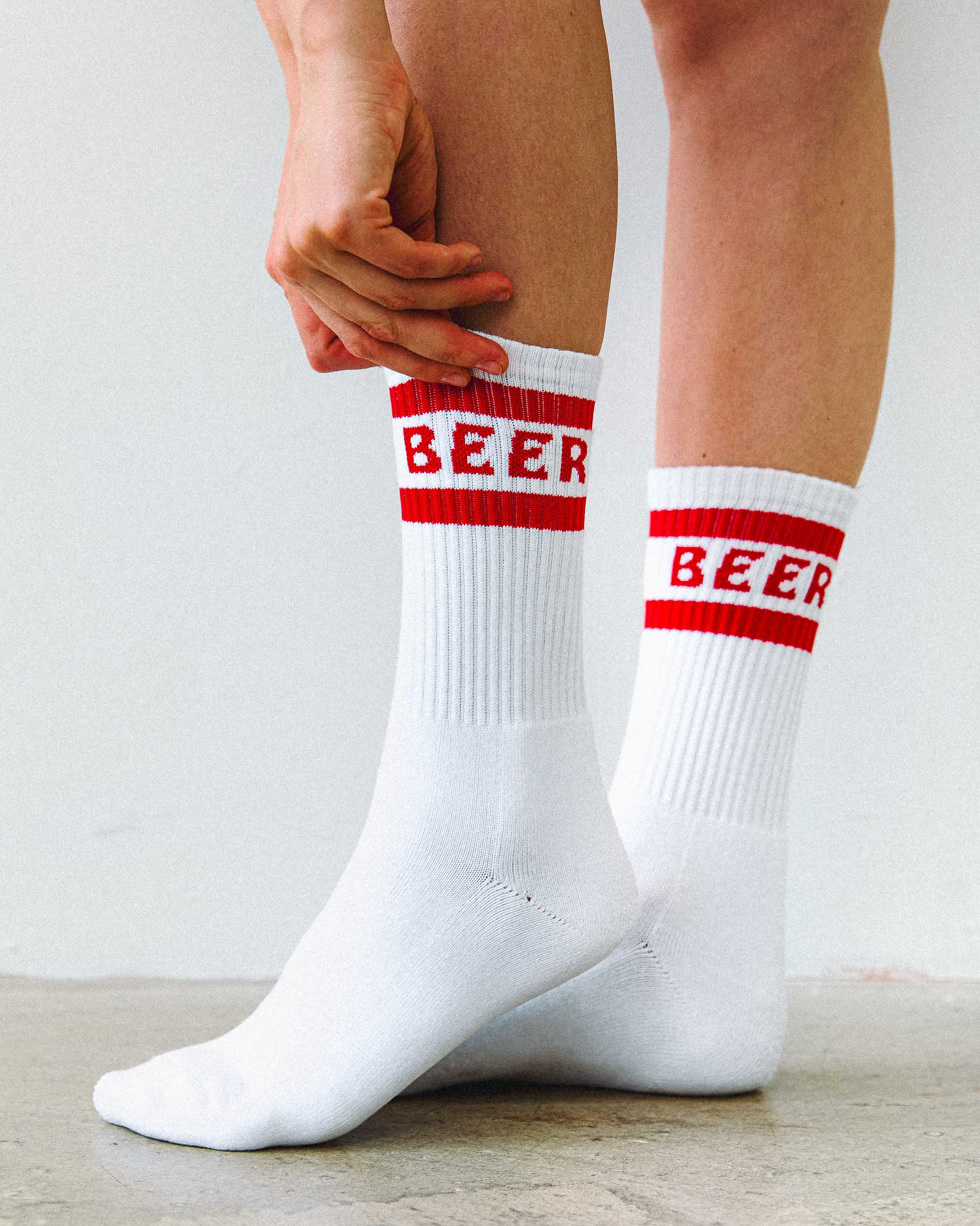 White cotton crew socks with "Beer" written on them in red writing.
