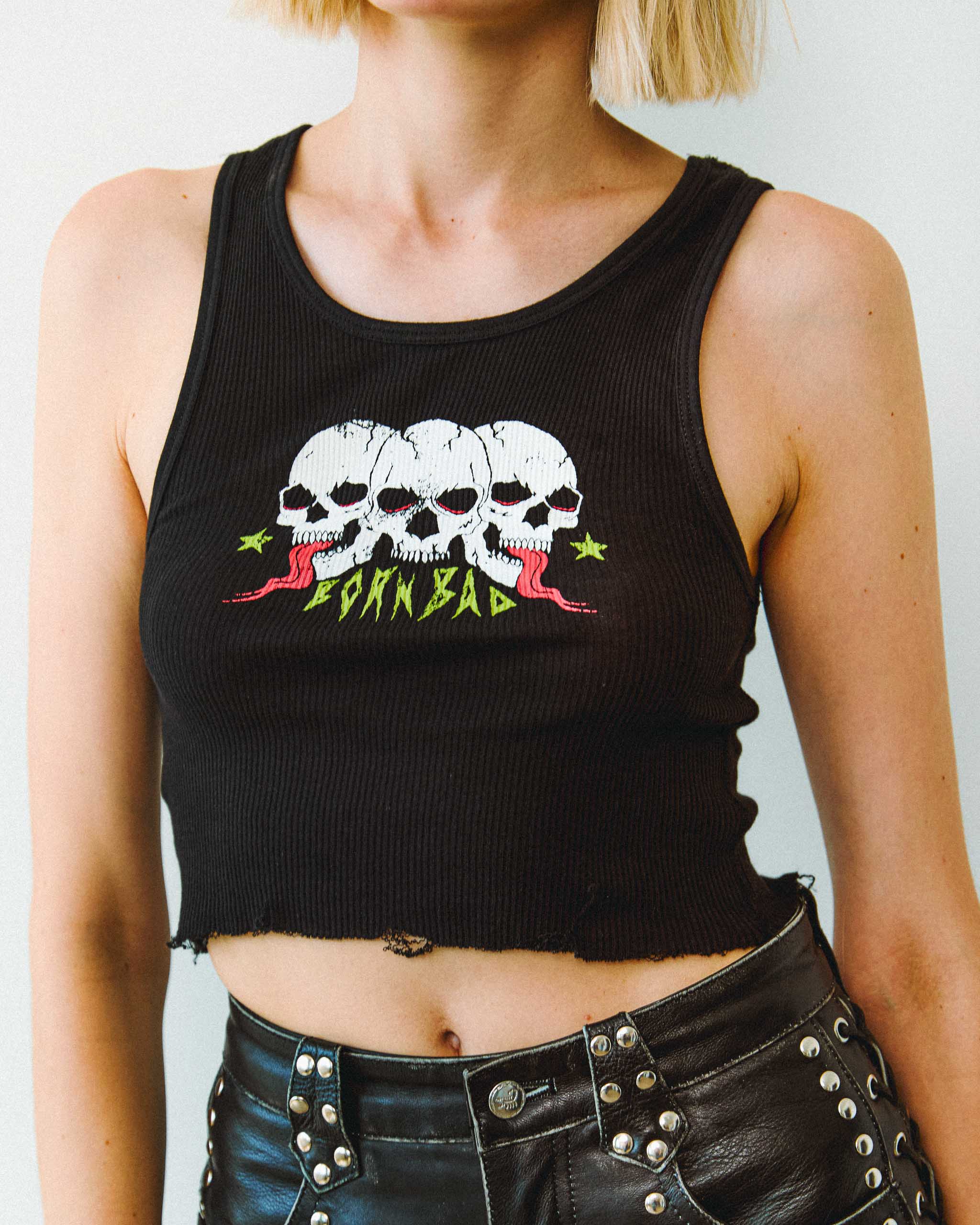 A gothic black tank top with 3 skulls printed on the front, and studded leather shorts.