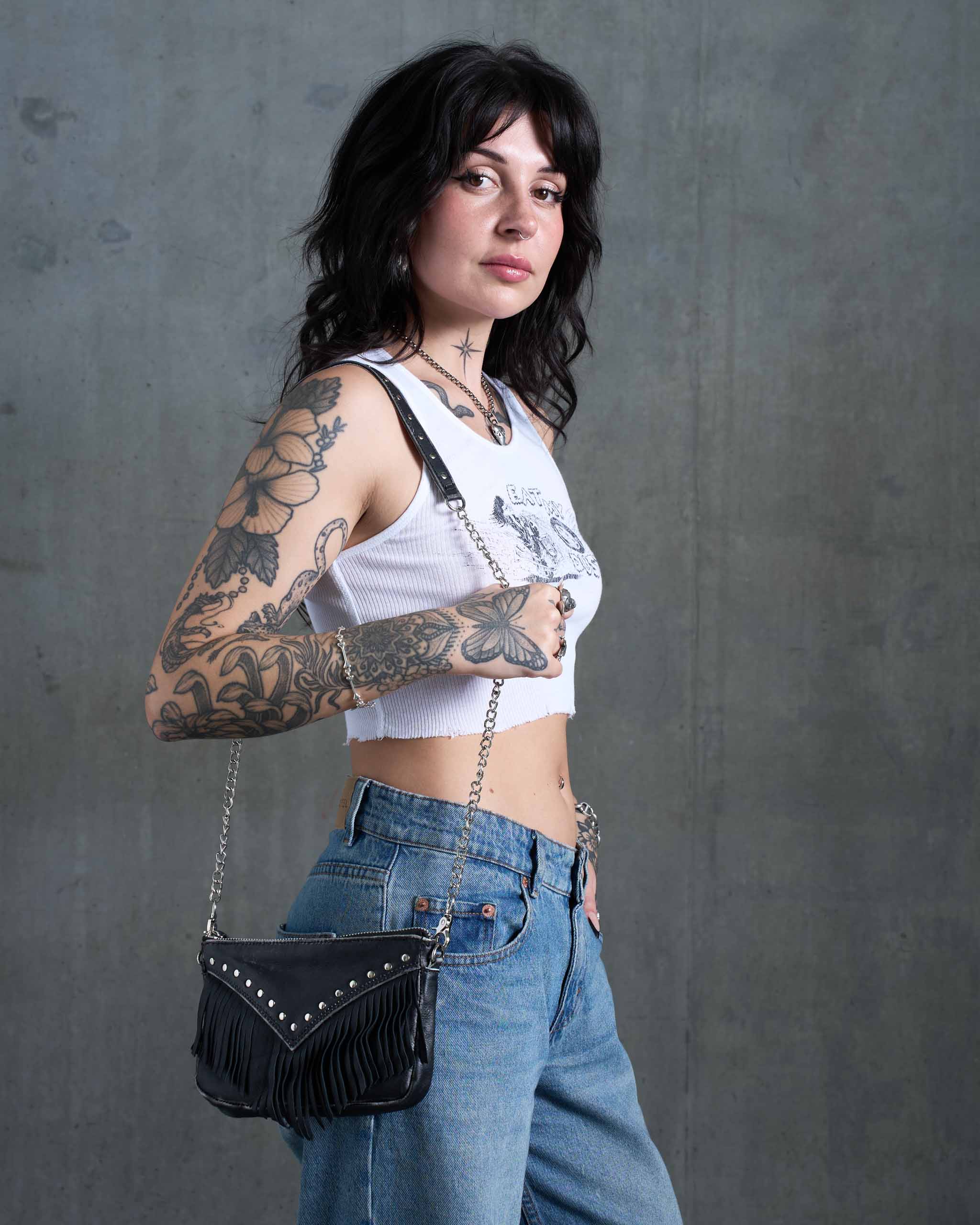 A tattooed alternative model wearing a gothic western evening bag.