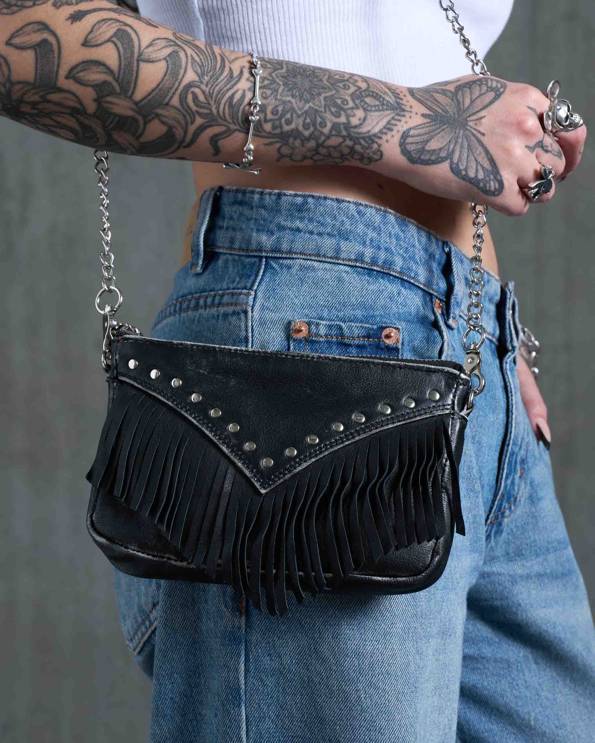 A tattooed model wearing a gothic western mini bag with chain strap.
