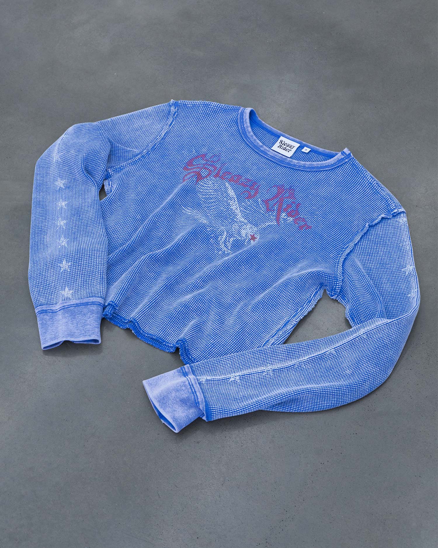 A blue waffle knit long sleeve top with a heavy faded wash, swooping eagle screen print and stars up the sleeves.