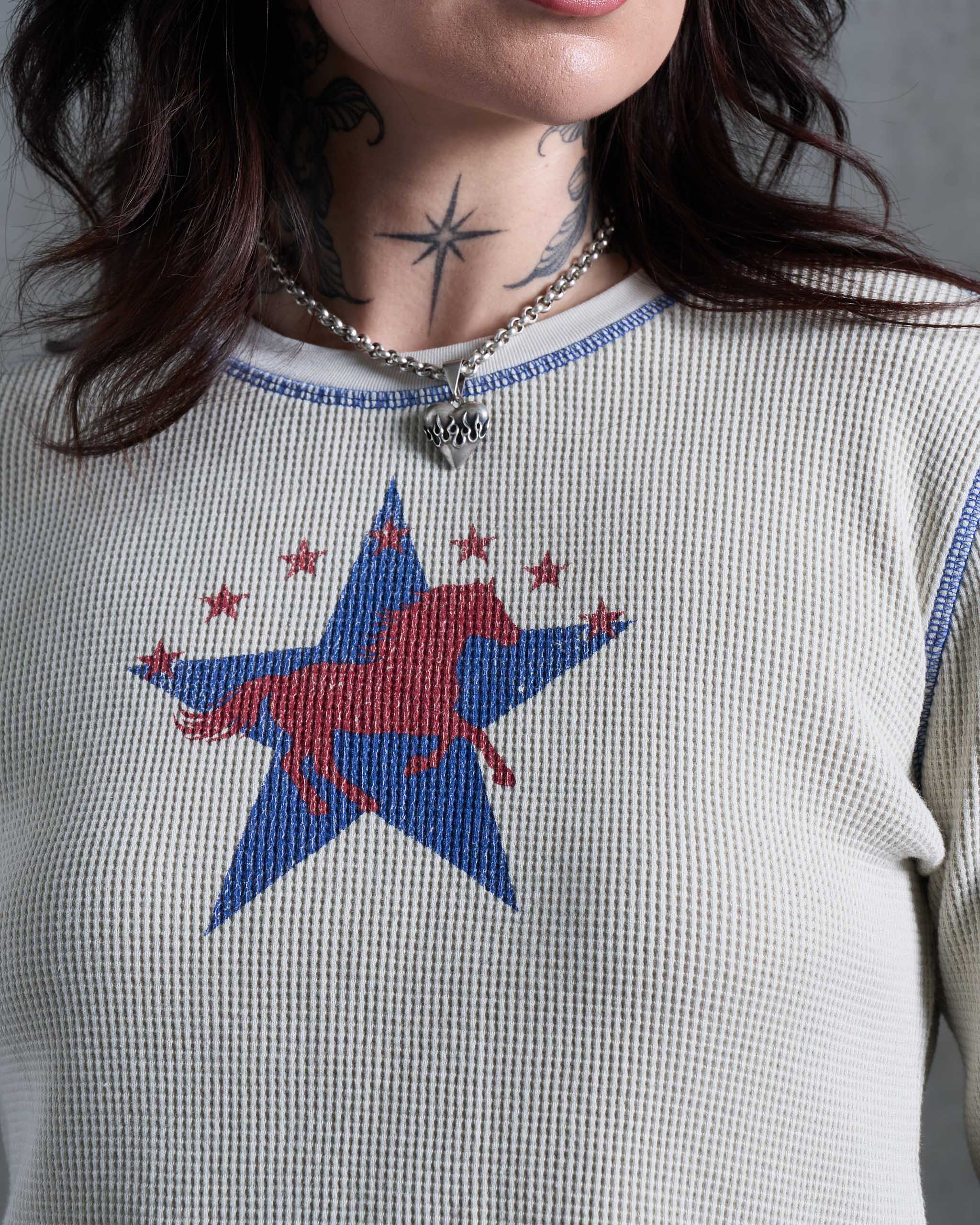 Close-up of a person wearing a waffle knit top with a large blue star and red horse graphic on the chest, plus blue trim at the neckline.