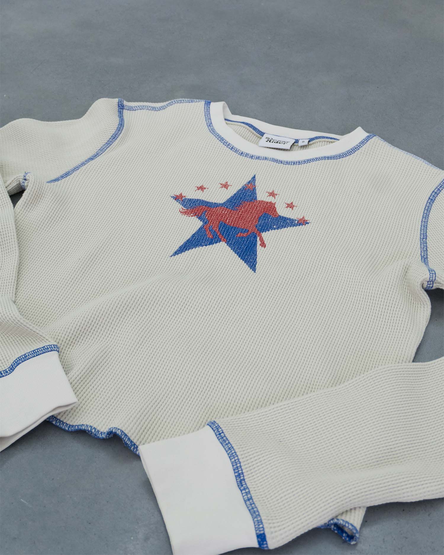 An off-white waffle sleeve top with a western horse screen print and blue contrast stitching.