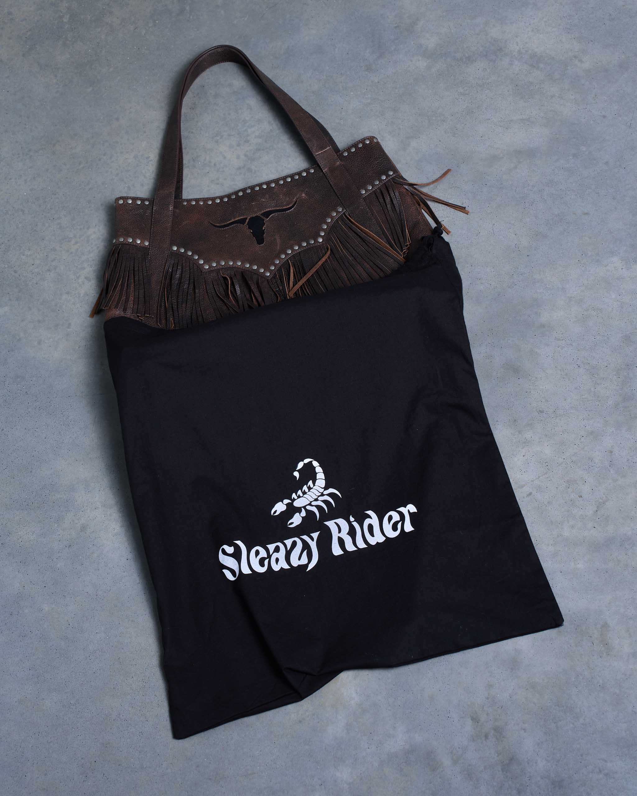 A big brown wild western leather bag halfway coming out of a protective Sleazy Rider dust bag.
