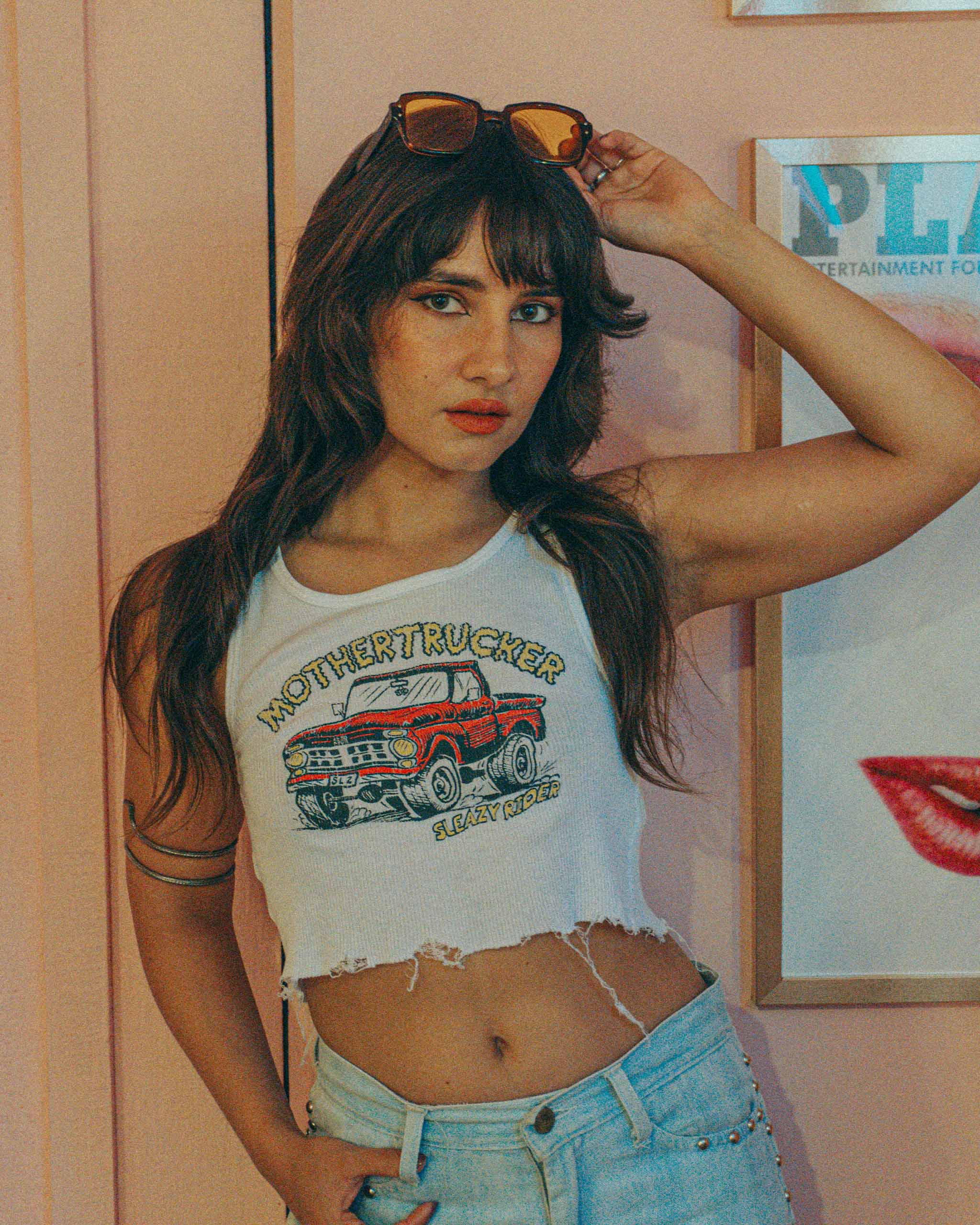 Woman wearing a "Mothertrucker" graphic tank top with 70's sunglasses and studded jeans.