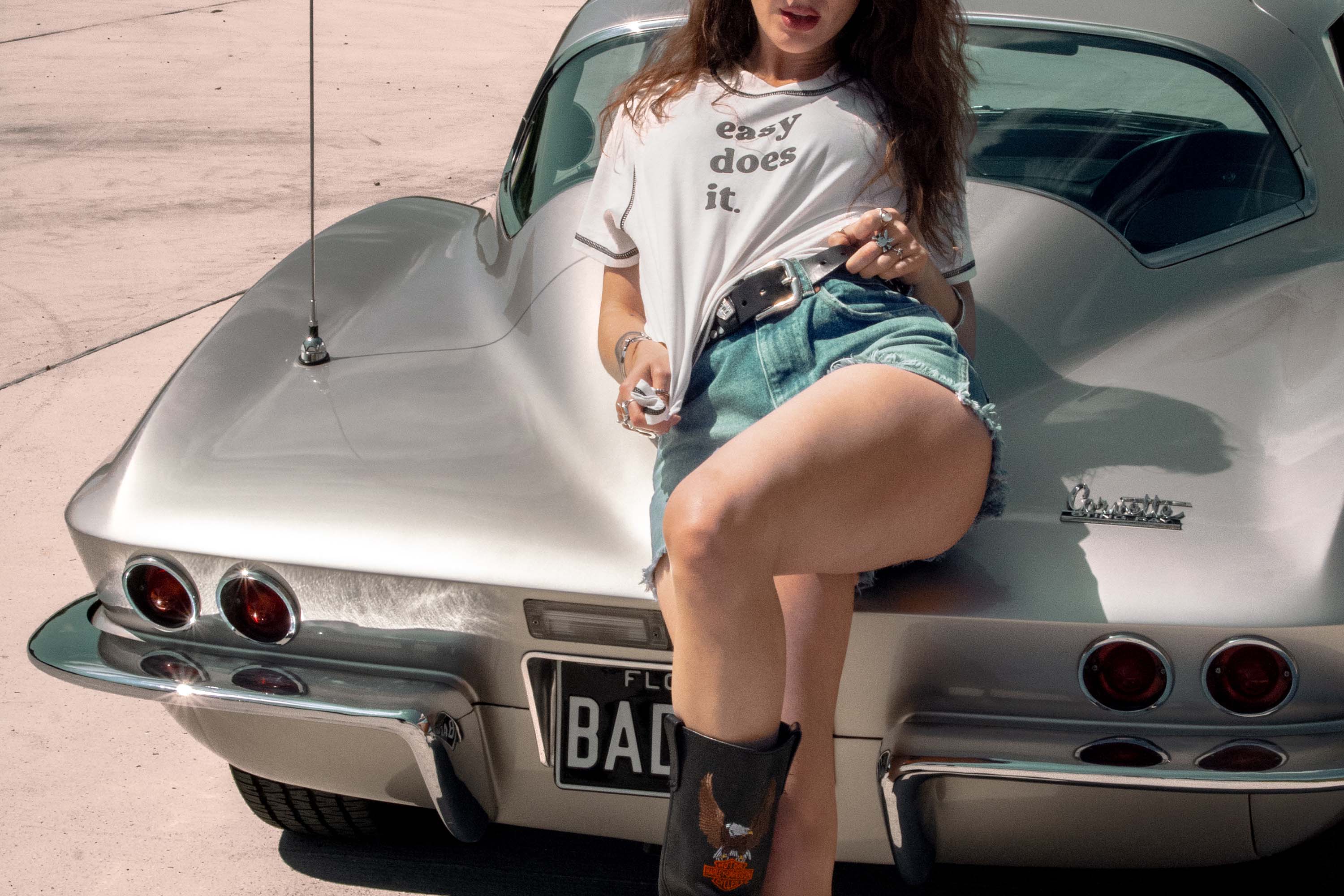 Woman sitting on a classic Corvette with a casual pose