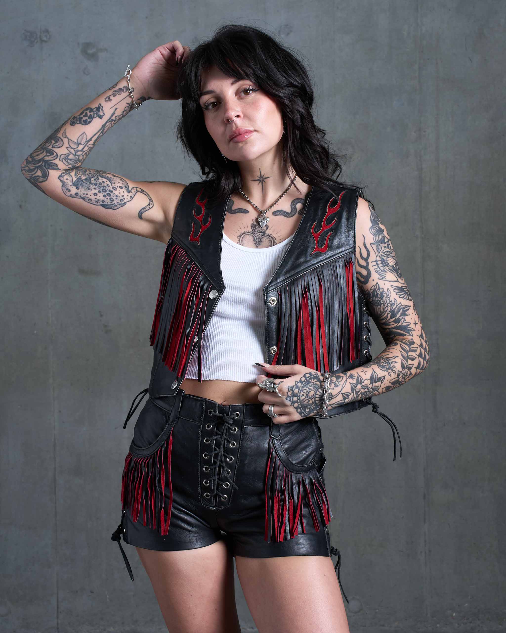 A tattooed model wearing the Outlaw biker fringe leather vest. Made from black leather with red suede flames details.