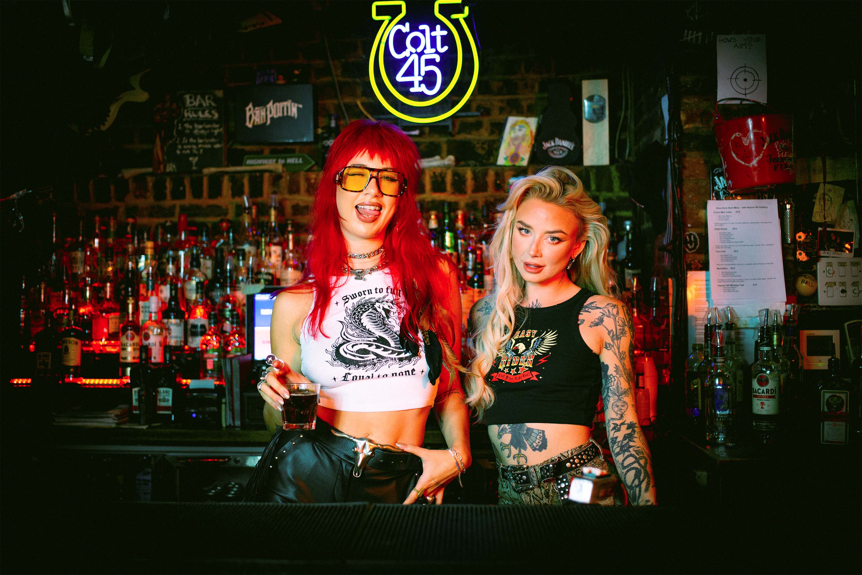 Amy Valentine and Rhianon Brailsford wearing Sleazy Rider tank tops in a dive bar