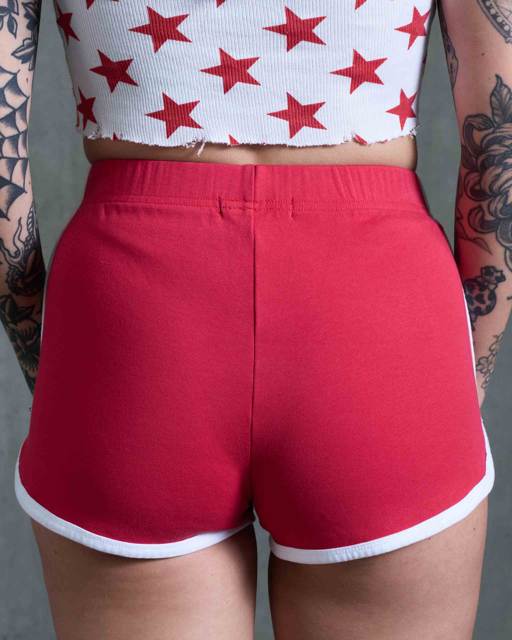 A tattooed woman wearing some vintage 80's sports shorts, rear view.