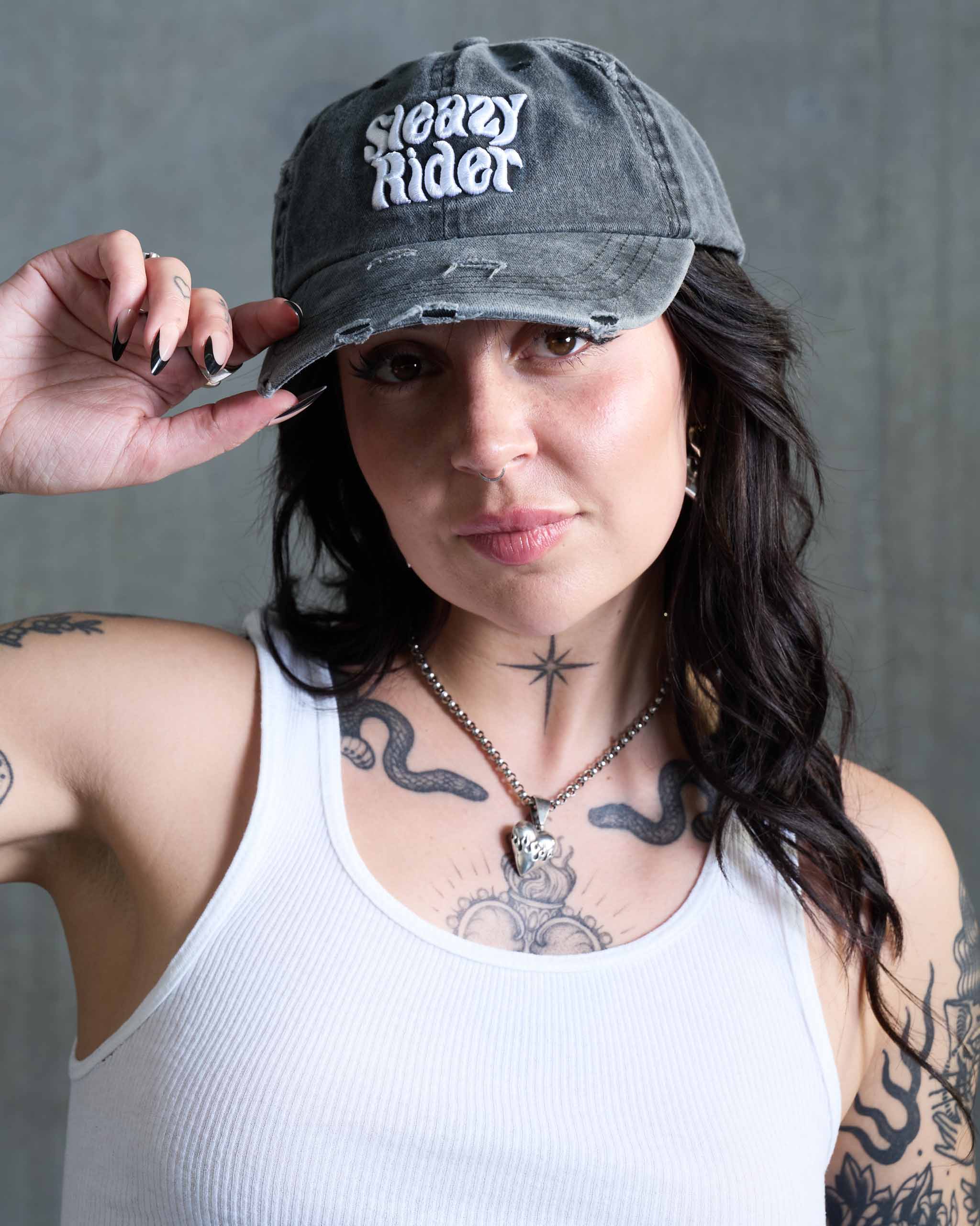 An alt woman wearing a Sleazy Rider cap, acid washed and distressed.